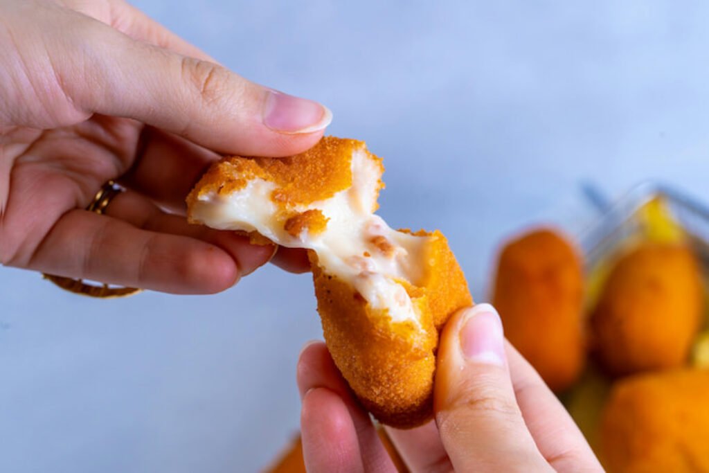 Pessoa abrindo uma bolinha de queijo. 