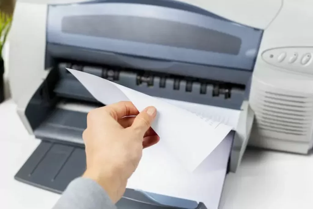 Uma pessoa mexendo em uma impressora.