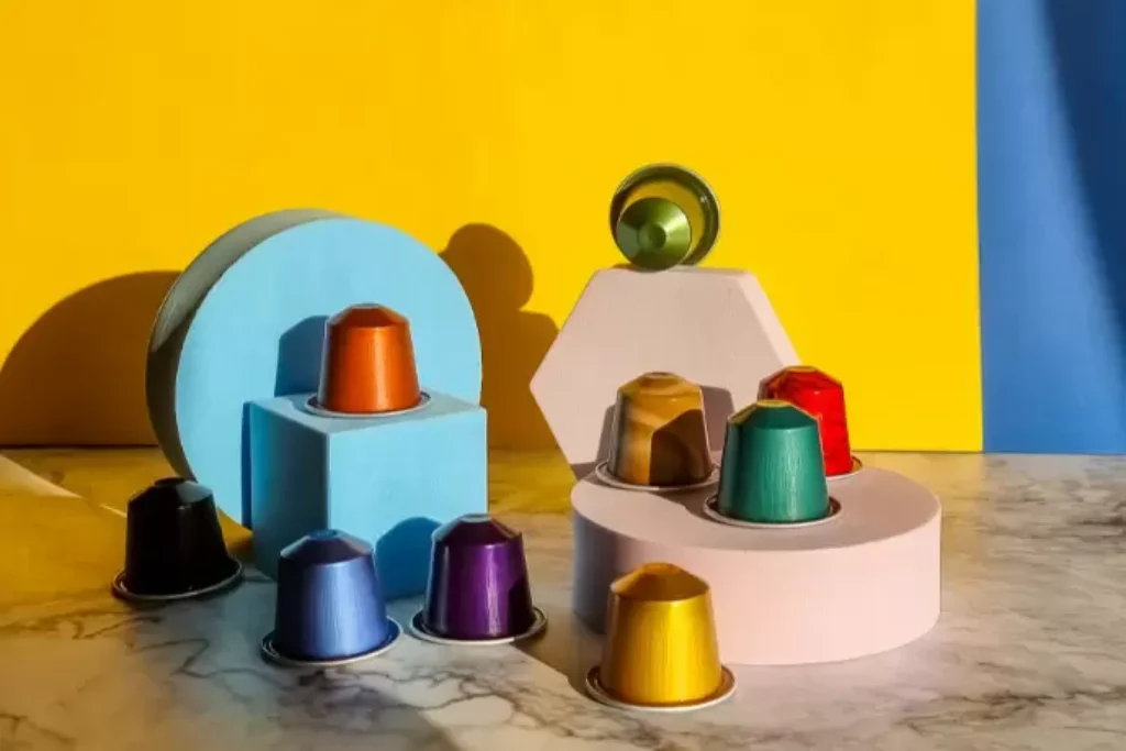 Duas cafeteiras e algumas cápsulas de café.