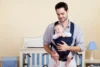 Um homem segurando um bebê com um canguru.