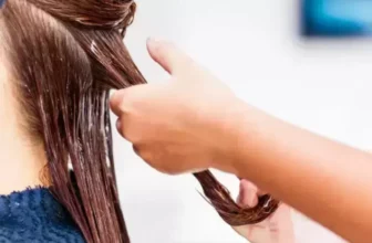 Uma pessoa aplicando uma máscara de hidratação no cabelo de uma outra pessoa.