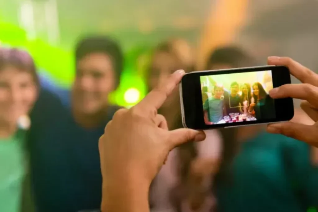 Uma pessoa tirando fotos de outras pessoas com o celular.