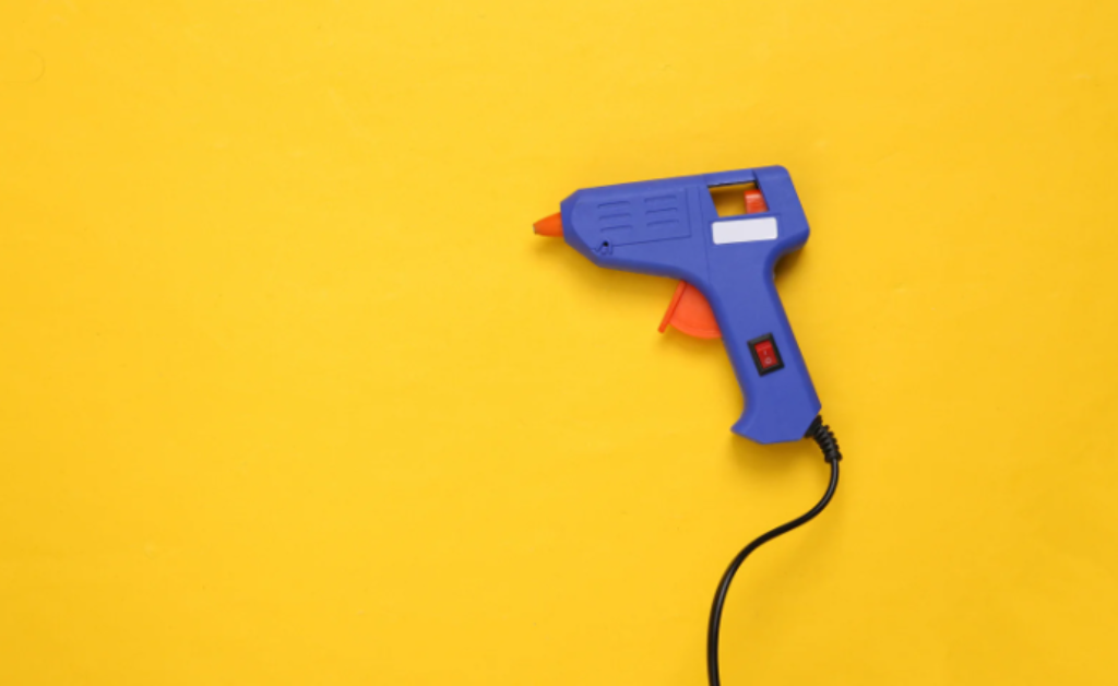 pistola de cola quente e fundo amarelo